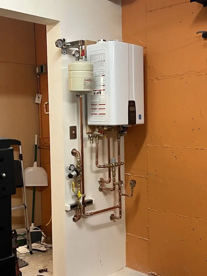 Plumbing technician inspecting water heater connections in Ossian